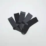 Pack de cinco pares de medias de caña media en tonos grises y negros con diferentes diseños: un par liso negro, un par gris con lunares negros, un par gris oscuro liso, y dos pares a rayas horizontales en diferentes tonos de gris.