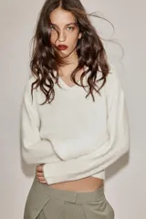Jersey de punto con mezcla de lana y alpaca, color amarillo mostaza, con cuello en pico y manga larga. Presenta acabados en rib en puños y bajo.