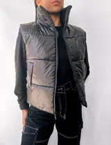 Chaleco puffer negro con cuello alto y cierre frontal con cremallera. Tiene bolsillos laterales y diseño acolchado.