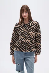 Campera estilo camisa (shacket) cropped, con cuello, cierre frontal y dos bolsillos con tapa en el pecho. Presenta un estampado de cebra en tonos beige y negro.