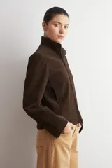 Chaqueta de cuero color marrón oscuro, con cuello alto, cierre frontal y diseño minimalista de corte recto.