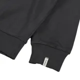 Buzo de cuello redondo en color negro, con diseño de estampa gráfica pequeña en el pecho que incluye texto y flores amarillas.