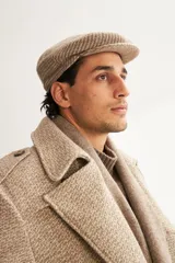 Boina con visera de lana fina uruguaya natural, sin teñir, con diseño de tejido texturizado en tonos beige y marrón.