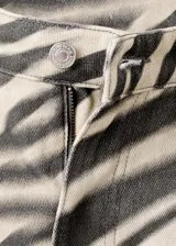 Jeans de corte wide leg con estampado animal print tipo cebra en tonos beige y negro, tiro medio y diseño de cinco bolsillos.