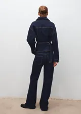 Pantalón de jean estilo flare con tiro medio, cierre de cordones en la cintura, cinco bolsillos y costuras a contratono.