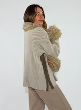 Saco de punto acanalado en color beige, con cierre frontal y detalles de piel sintética en el cuello y los puños.