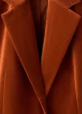 Blazer de terciopelo color marrón, con solapas de muesca, cierre frontal de un botón y dos bolsillos de parche delanteros.