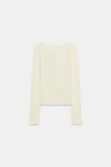 Camiseta slim fit de algodón color crudo, con cuello redondo, manga larga y cierre frontal de múltiples botones pequeños.