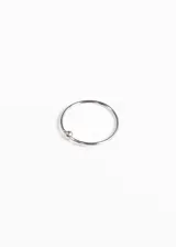 Piercing de acero quirúrgico hipoalergénico, con forma de aro abierto y bolita decorativa.