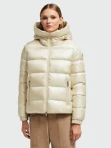 Campera puffer Moncler modelo Biron, color beige perlado, con capucha integrada, cierre frontal y bolsillos laterales con cierre. Presenta diseño acolchado horizontal y logo de la marca en la manga.