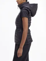 Chaleco negro acolchado con capucha, cierre frontal con cremallera, cinturón con hebilla metálica y bolsillos laterales con cremallera.