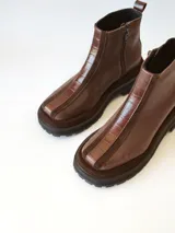 Bota corta de cuero en tonos chocolate, con diseño de paneles texturizados y suela track robusta de goma.
