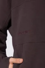 Buzo canguro de corte oversize en color gris con efecto lavado desgastado. Presenta diseño con recortes horizontales, capucha amplia y puños acanalados con etiqueta de marca en la manga.