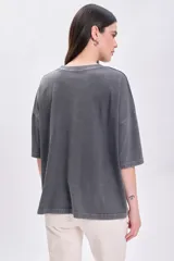 Remera manga corta de color gris oscuro con efecto lavado, corte oversize y cuello redondo. Cuenta con pequeños apliques brillantes distribuidos por toda la prenda.