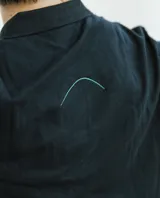 Remera tipo polo azul marino con cuello y puños acanalados en el mismo tono, mangas cortas. Cuenta con el nombre de la marca impreso en vertical sobre el lado derecho del frente y un bordado pequeño en el pecho izquierdo.