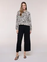 Camperita liviana de silueta entallada y largo a la cintura, con cuello camisero, cierre frontal de botones, mangas largas y bolsillos con solapa en el pecho. Presenta estampado animal print.