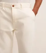 Pantalón de hombre color crudo, de corte recto, confeccionado en sarga de algodón. Cuenta con cintura con trabillas, cierre tradicional, bolsillos y etiqueta aplicada.
