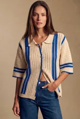 Cardigan oversize de crochet en color beige con rayas verticales y detalles en azul, cuello polo, mangas cortas y cierre frontal con botones.