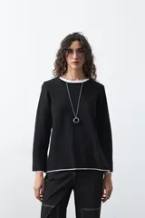 Sweater de tejido de punto con silueta recta y calce relajado. Presenta un diseño liso en color negro con detalles de vivos en contraste color blanco en el cuello redondo, los puños y el ruedo.