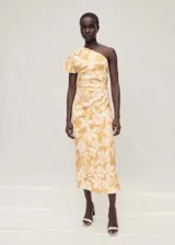 Vestido midi de lino con estampado floral en tonos amarillos y blancos. Presenta un diseño asimétrico con un solo hombro, cintura drapeada y una abertura lateral en el bajo.