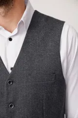 Chaleco azul con textura de espiga, cuello en V, cierre abotonado y bolsillos delanteros.