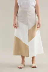 Falda larga de lino con diseño de cortes diagonales en bloques de color blanco, beige y tostado, de corte evasé y caída fluida.