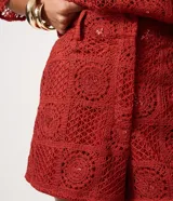 Short corto de crochet Marfinno color rojo, con diseño calado, bordado abstracto integral, aplicación de lentejuelas, pretina con pasadores y cierre delantero. Cuenta con forro interior.