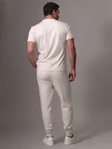 Pantalón de jogging color crema con cintura elástica ajustable con cordón, bolsillos laterales con cierre y puños ajustados.