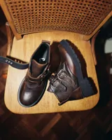 Botas cortas de cuero vacuno color marrón con hebillas y suela de goma negra.