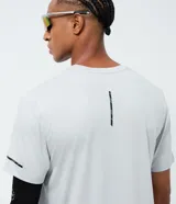 Remera deportiva de manga corta y cuello redondo color gris, con detalles gráficos reflectantes en la espalda y mangas.