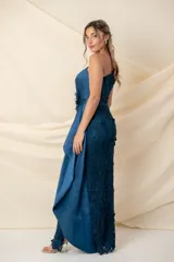 Vestido largo asimétrico de encaje color bordó, con un solo bretel y detalle de apliques florales en hombro y cintura. Presenta una pieza lateral de tafeta que cae desde el escote y un tajo pronunciado en el costado.