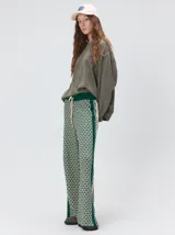 Pantalón de punto jacquard con diseño geométrico texturizado, de corte holgado y pierna ancha. Presenta tiro medio, cintura elástica con cordón ajustable y aberturas laterales en el ruedo.