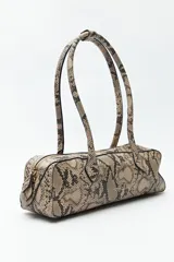 Cartera baguette cilíndrica con estampado de piel de serpiente en tonos beige y negro. Asas cortas y cierre superior con cremallera.