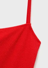 Malla enteriza roja de tejido canalé, con escote recto y tirantes finos. Cuenta con forro interior para mayor comodidad.