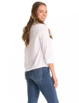 Camisa blanca de corte recto y estilo clásico, con cuello solapa, cierre frontal oculto y mangas largas con puños. Presenta dos bolsillos frontales decorados con apliques de tachas metálicas en el borde superior.