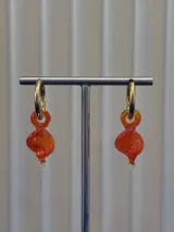 Aros tipo argolla de acero quirúrgico con dije colgante de cristal de Murano en forma de espiral color naranja.
