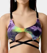Corpiño con estampado tie-dye en tonos violeta, verde y amarillo, con tiras de cuero sintético negro y aros metálicos.