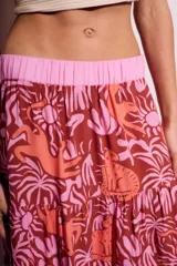 Falda larga de viscosa con estampado de animales y plantas en tonos marrón, naranja y rosa. Tiene cintura elástica rosa.