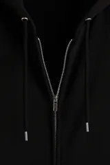 Campera con capucha de felpa de peso medio con interior cepillado suave. Presenta hombros caídos, cierre frontal, bolsillos tipo canguro y terminaciones en punto acanalado en puños y bajo.