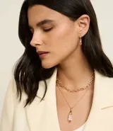 Conjunto de accesorios compuesto por un collar de cadena de eslabones, un collar con dije de cristal y un par de aros tipo argolla con dije de cristal. Piezas con acabado en tono dorado.