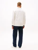 Camisa blanca de algodón con textura moteada, corte oversize, cuello inglés, bolsillo de parche en el pecho y parche de Tommy Jeans en el bolsillo.