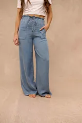 Pantalón wide leg de denim liviano en color celeste, con cintura elástica fruncida y cordón ajustable. Cuenta con bolsillos frontales aplicados.