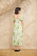 Vestido midi blanco con estampado floral en tonos verdes, escote en V, mangas cortas abullonadas y corte evasé con abertura lateral.