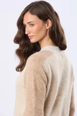 Buzo tejido de punto con diseño de bloques de color en tonos rosa, beige y gris. Presenta cuello redondo, mangas largas y puños acanalados.