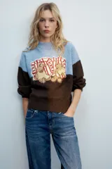 Jersey de punto con cuello redondo y manga larga, de diseño combinado en color celeste en la parte superior y marrón en la inferior y las mangas. Cuenta con un diseño estampado de ositos en el frente.