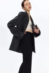 Leggings negros de punto pesado de corte sastre, con elástico oculto en la cintura, bolsillos decorativos en la parte trasera, pliegues cosidos al frente y pequeñas aberturas en los bajos.