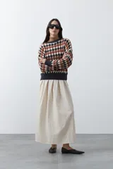 Sweater de punto con diseño geométrico de rombos en tonos azul, marrón, beige y blanco. Presenta cuello redondo, puños y ruedo acanalados en color azul oscuro, con un calce relajado y mangas largas.