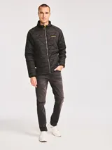 Campera acolchada de color negro con diseño de rombos, cierre frontal completo y cuello alto. Presenta el logo de la marca Caterpillar en un parche de silicona sobre el pecho.