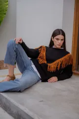 Sweater tejido de lana color negro con diseño de flecos de gamuza en tono tostado en la parte frontal, formando una silueta en V. Presenta cuello redondo y mangas largas.