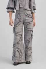 Pantalón de tiro alto con corte recto y diseño de cuadros en tonos grises y naranjas. Presenta detalles de volados aplicados en forma sinuosa a lo largo de las piernas.